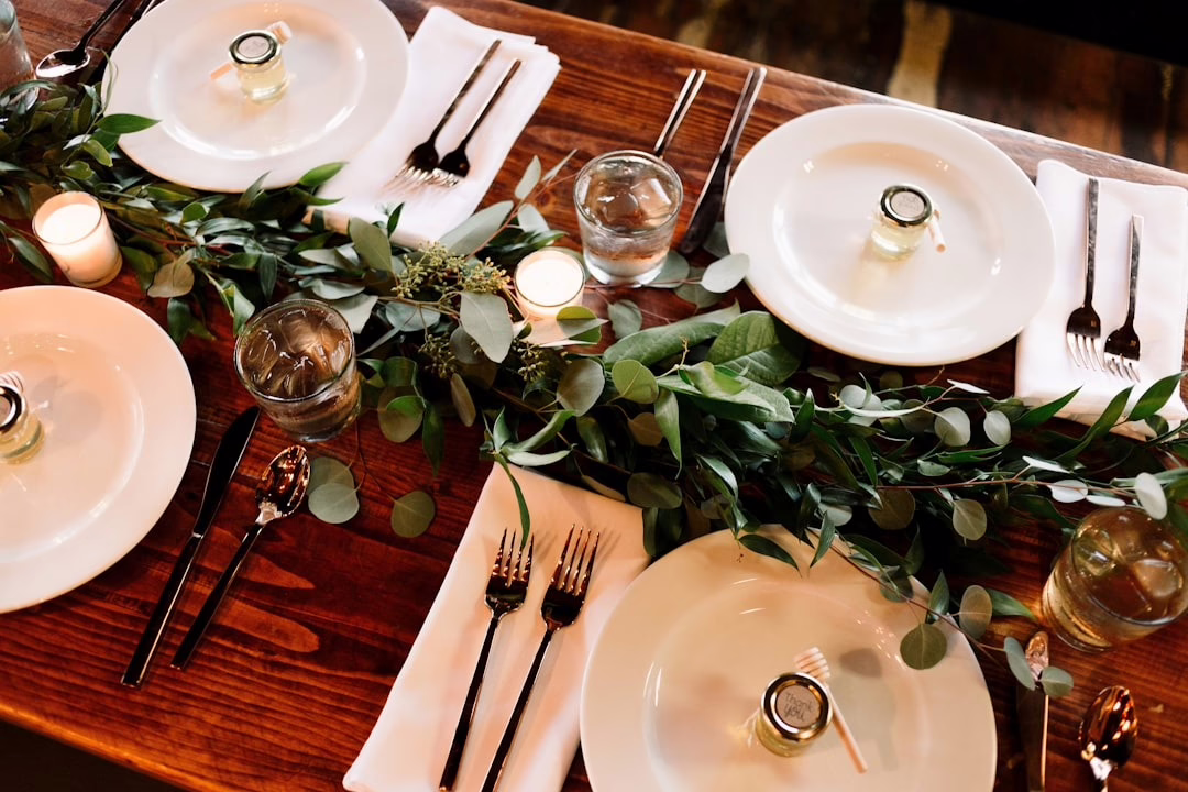 Silverware and drinks on a wooden table with floral decorations.